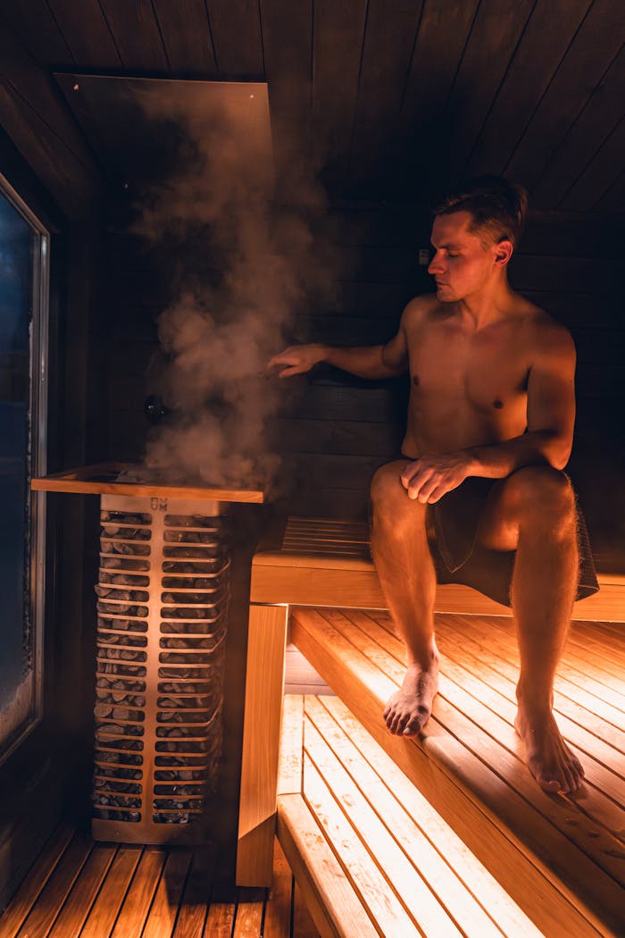 A man enjoys the warmth of a modern indoor sauna with an electric heater, highlighting Nordic design elements.