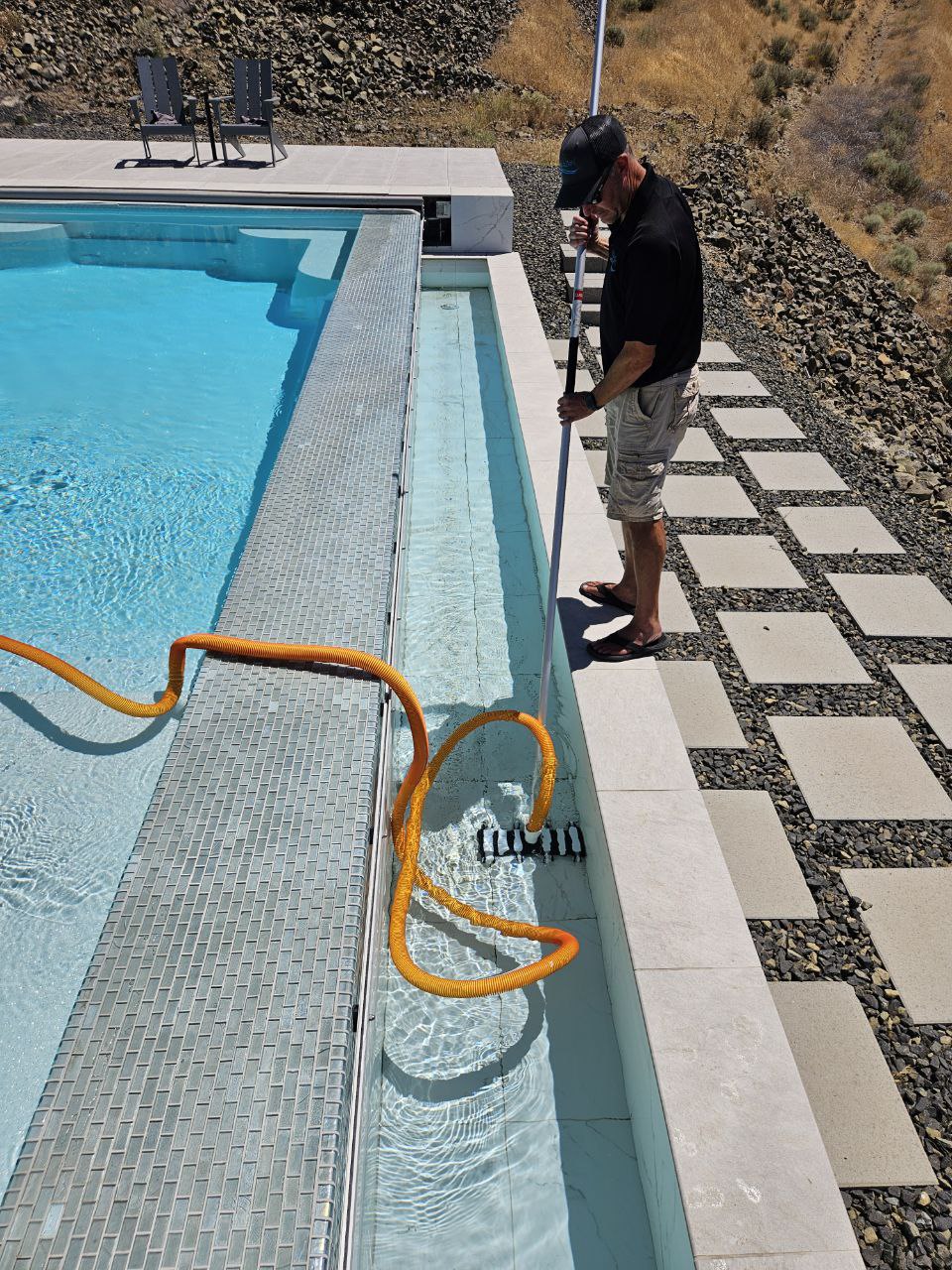 AquaZen co-owner Shawn Sanderson vacuuming a luxury infinity pool in the Tri-Cities area