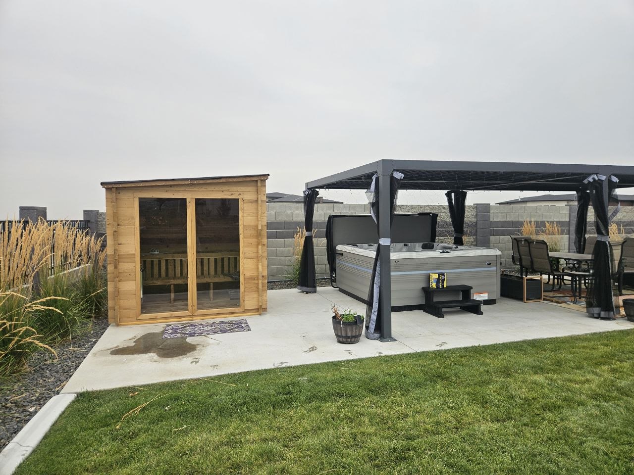Cedar outdoor sauna and Vita Spa hot tub under black pergola — backyard wellness delivery by AquaZen Pool Spa Sauna Tri-Cities WA