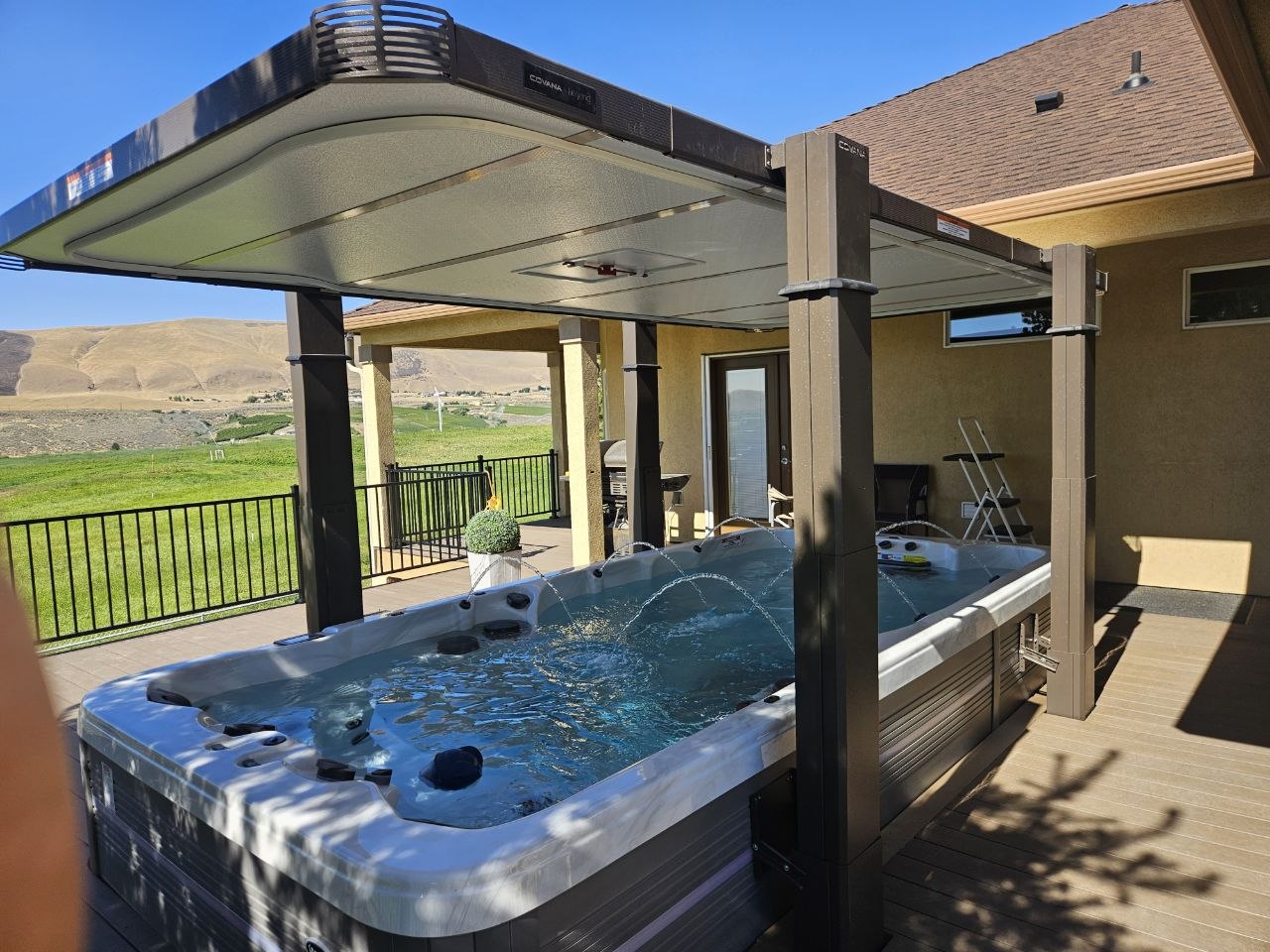 Swim spa with Covana automated gazebo cover fully open on trex deck with Eastern Washington hills view — AquaZen delivery Richland WA