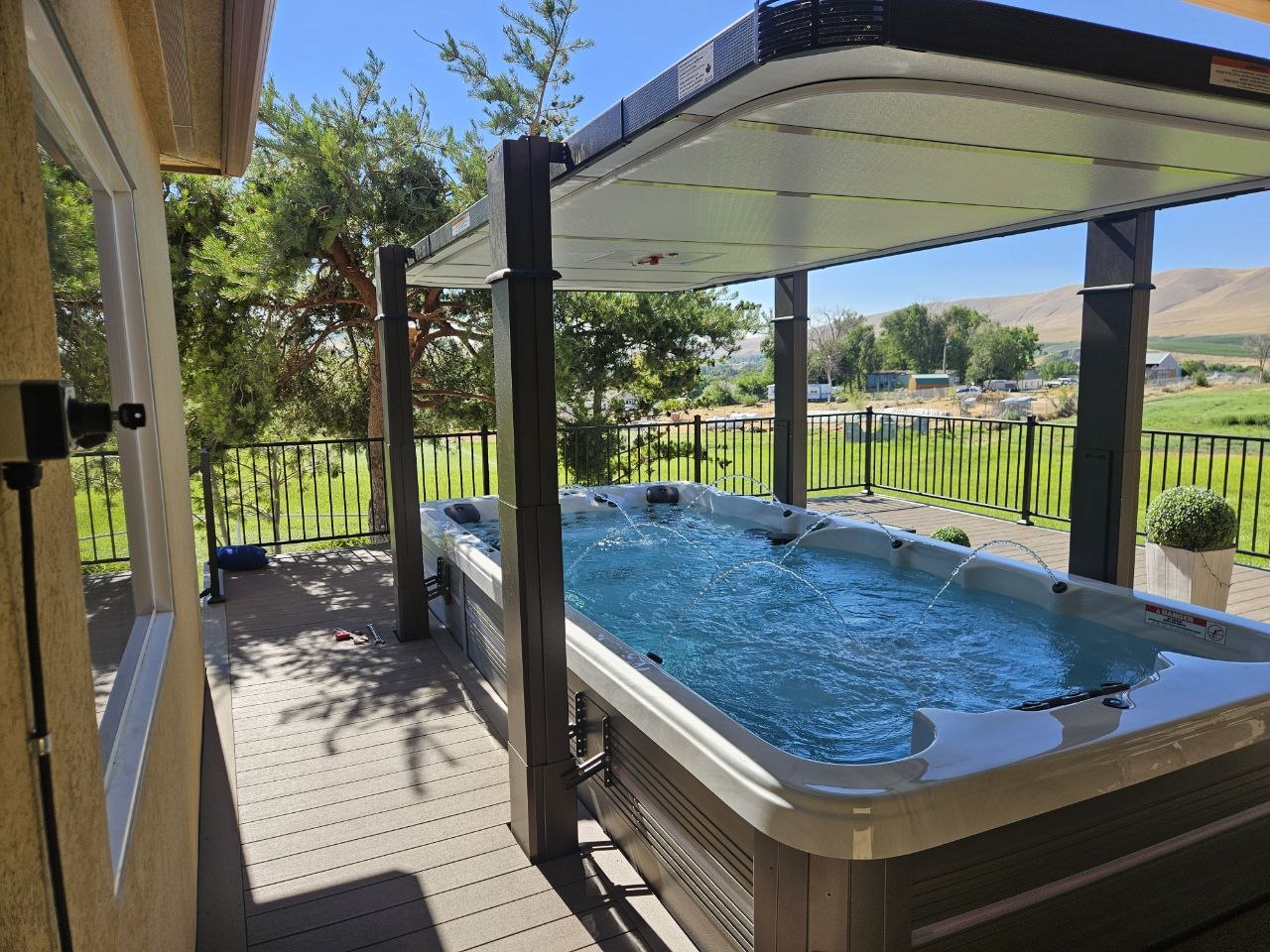 Swim spa under open Covana cover on trex deck with panoramic Eastern Washington hills and green field view — AquaZen Pool Spa Sauna
