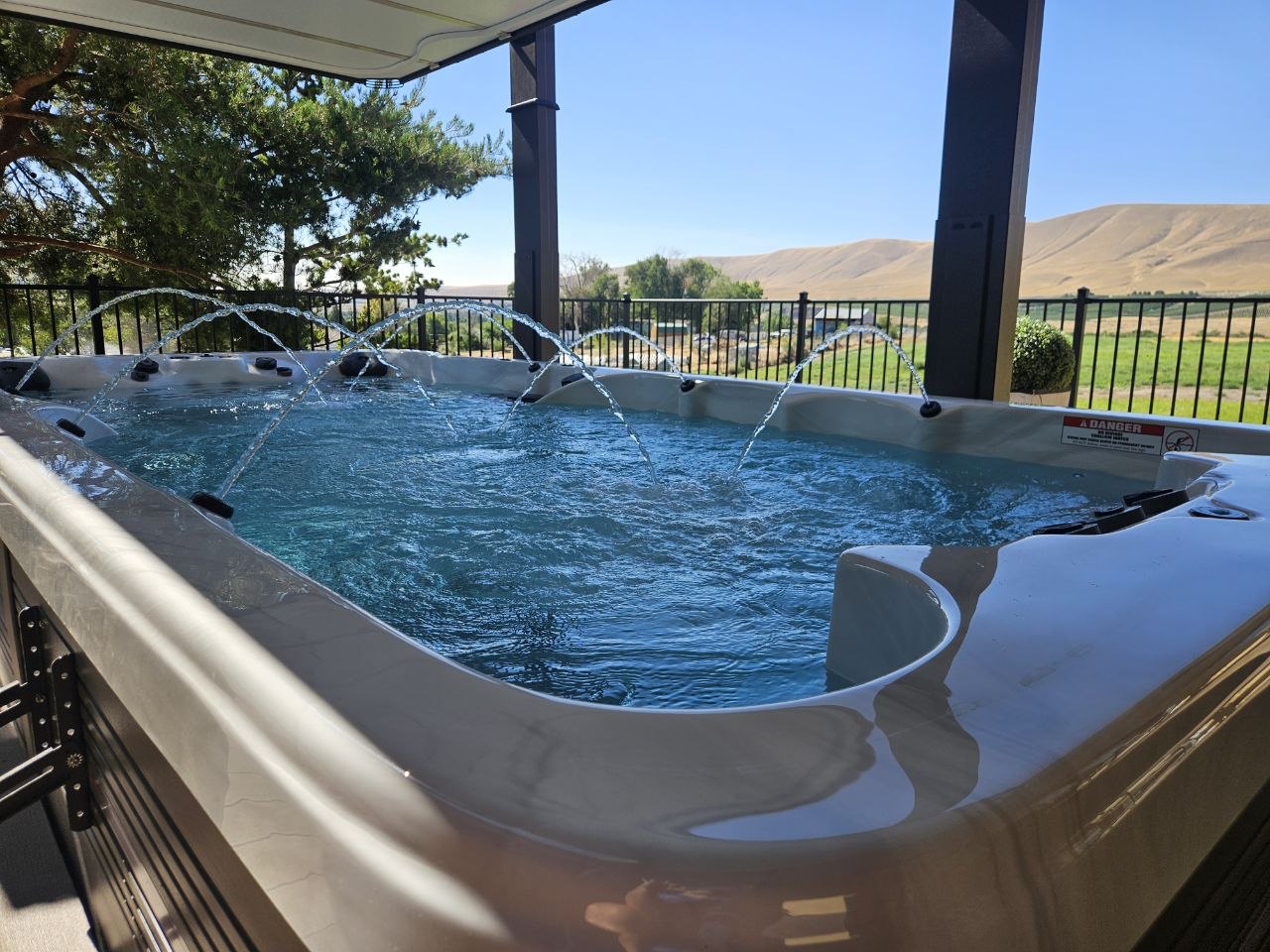 Swim spa with water jets running and Covana automated cover open, overlooking Eastern Washington hills — delivered by AquaZen Pool Spa Sauna Tri-Cities WA