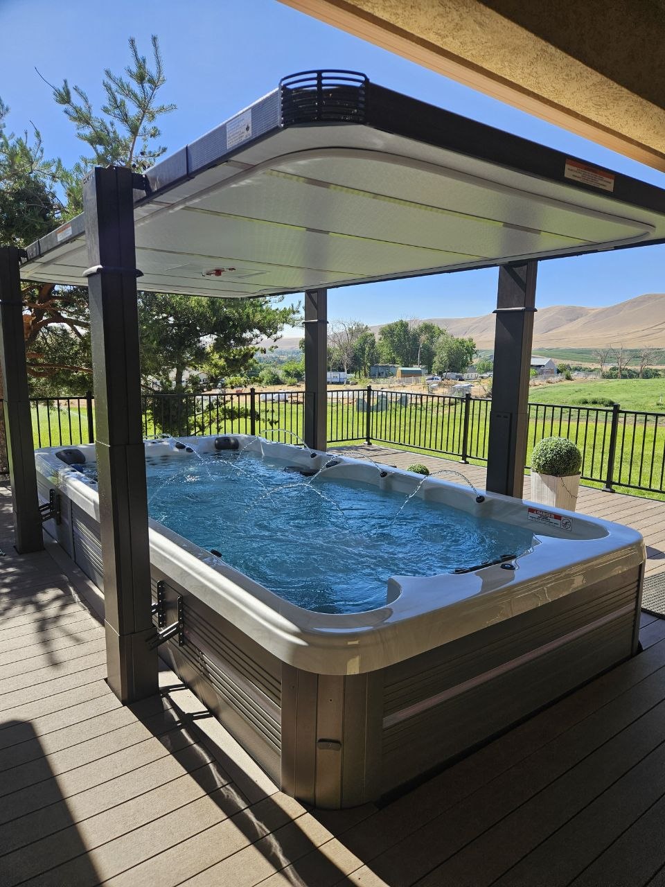 Swim spa with jets on under open Covana cover, panoramic view of Eastern Washington hills and farmland — AquaZen Tri-Cities WA